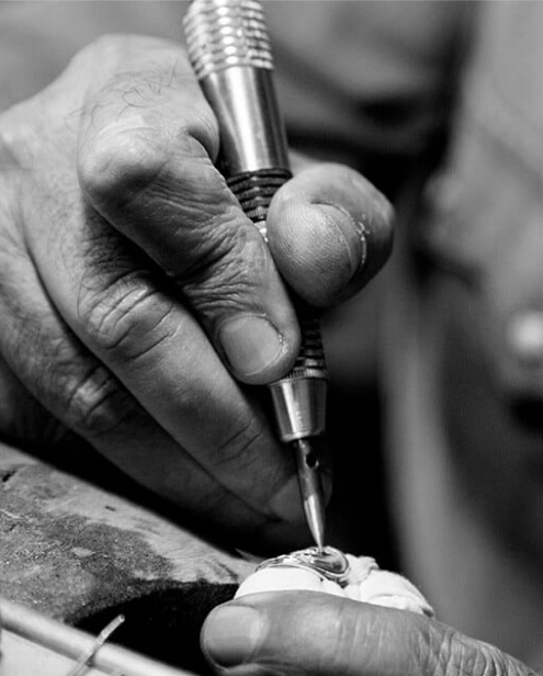 A jeweller setting a stone by hand at the bench